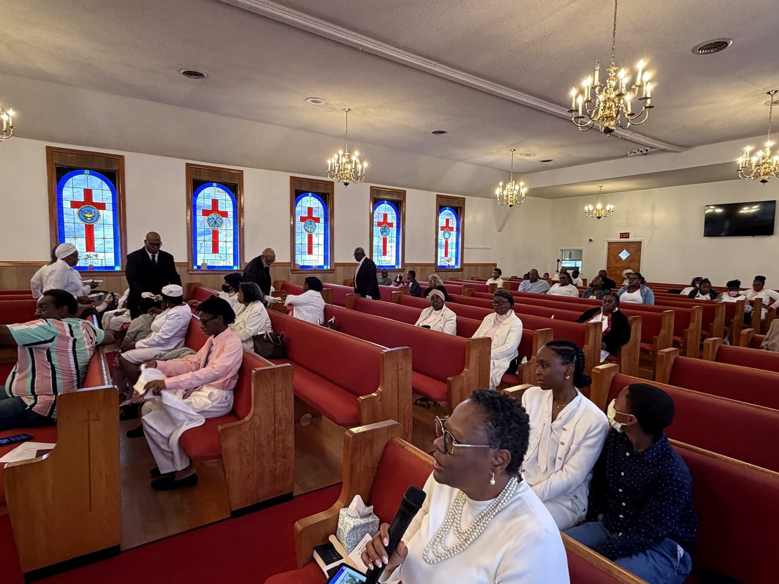 Congregation gathered for Sunday worship beneath the stained-glass windows